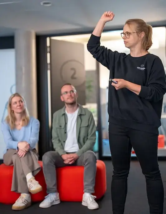 Resilienztraining im Großraum Hamburg: Anne Kritter zeigt Körperübung vor zwei Teilnehmern mit erhobenem Arm