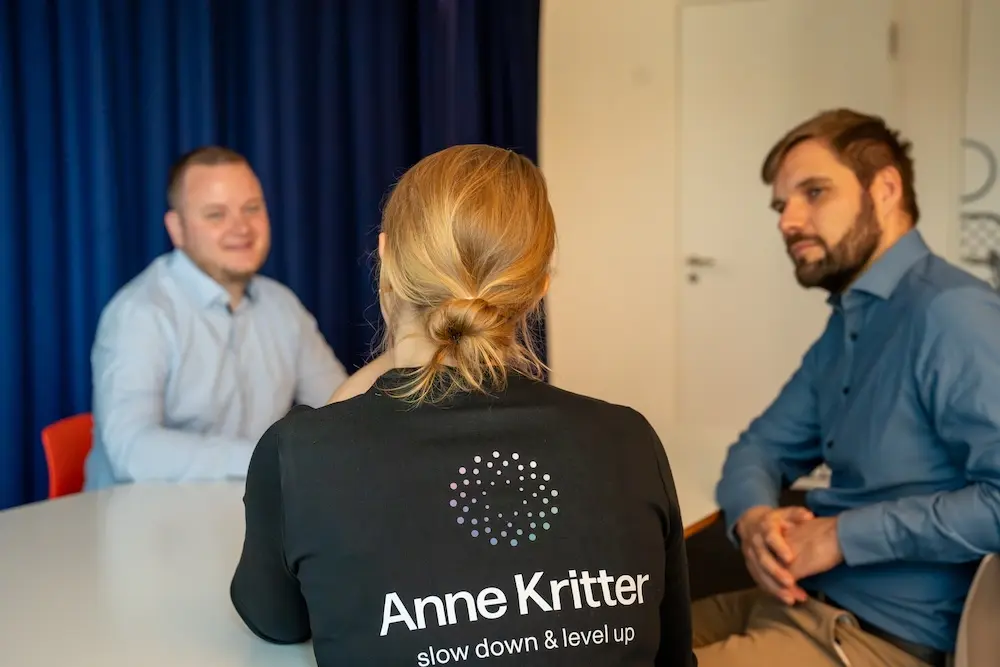 Rückenansicht von Anne im Beratungsgespräch mit zwei jungen Angestellten in HH