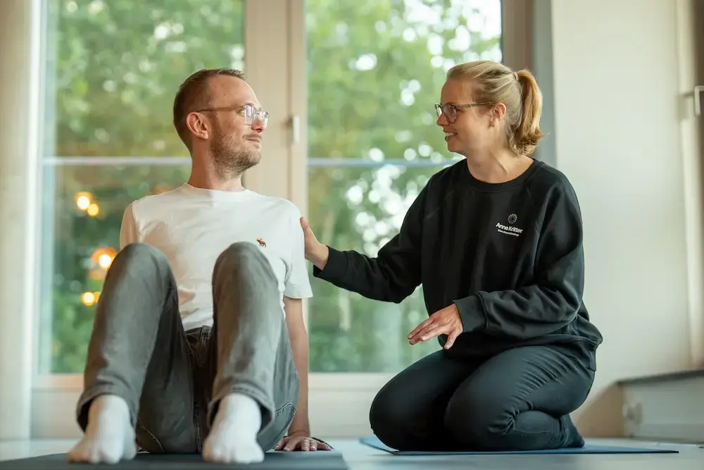 Anne Kritter mit Teilnehmer in Hamburg auf Yogamatte beim Bewegungstraining zur Stressbewältigung